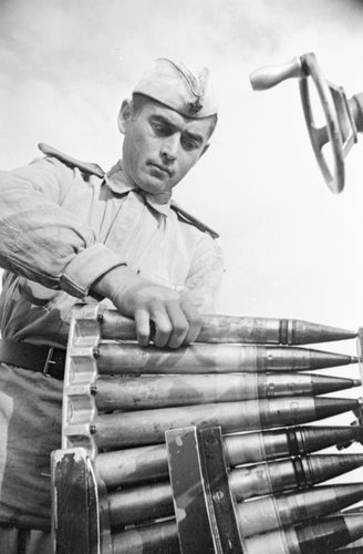 Заряжающий зенитного расчёта, сбившего пять немецких самолётов, рядовой М.Котолавидзе заряжает пушку обоймой со снарядами