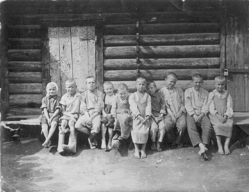 Группа эвакуированных детей дет. приемника управления НКВД г. Кирова (сидят на скамейке у деревянного дома)