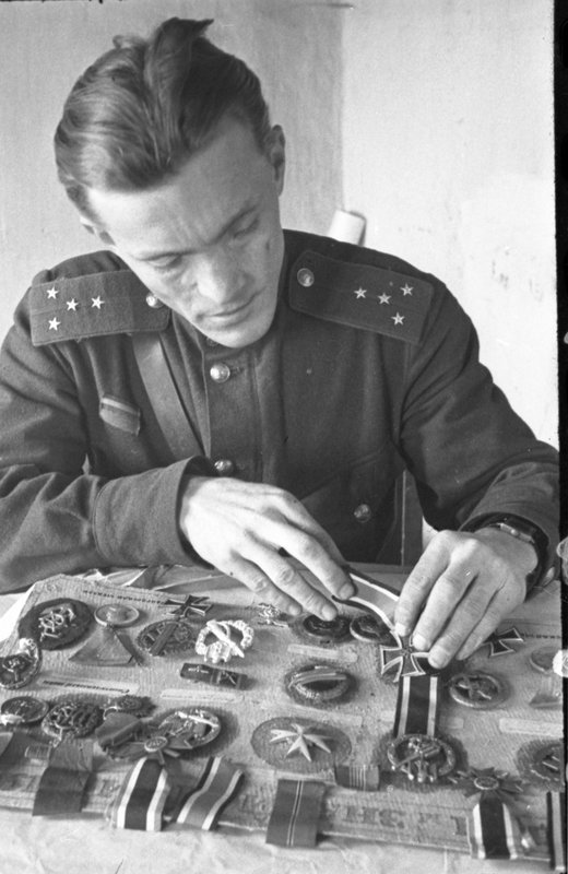 «Капитан РККА разбирает немецкие награды и знаки отличия и различия.»
