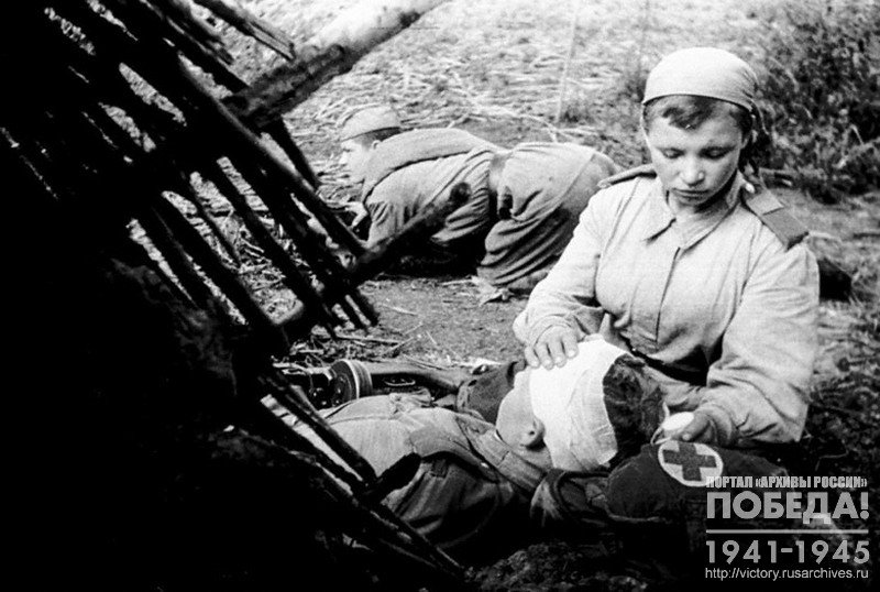 Санинструктор Н-ской части старший сержант Пономарева В. перевязывает раненого младшего лейтенанта Смирнова Н.С.