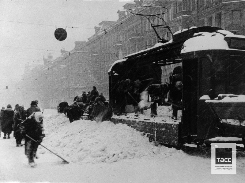 Locals clean city streets loading chipped ice and snow into the freight tram at 25 Octyabrya Prospekt. Leningrad (Nevsky Prospekt). March, 1942