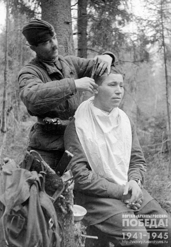 Red Army soldier-barber M. Bubnov is making a haircut to Lieutenant Panchenko