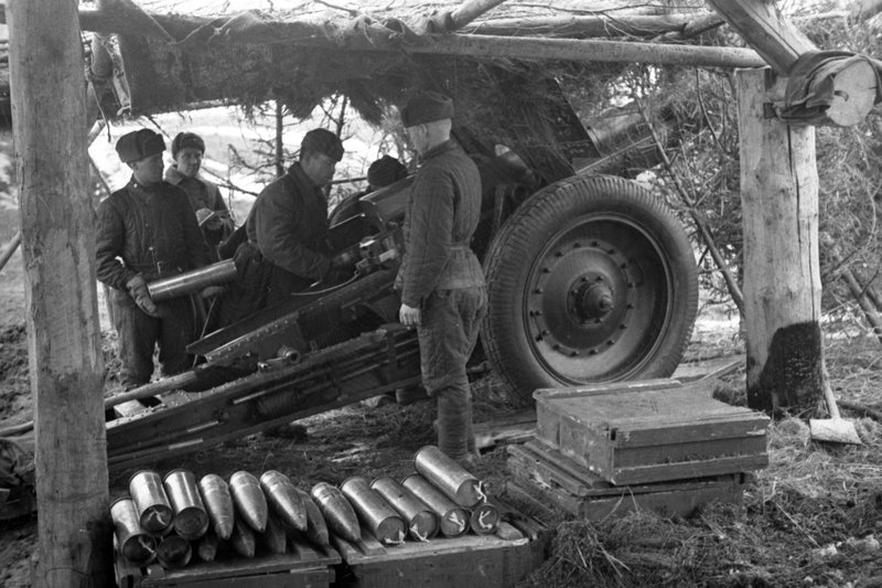 «Калининский фронт. Расчёт 107-мм пушки образца 1910/30 гг. заряжает своё орудие на замаскированной позиции.»