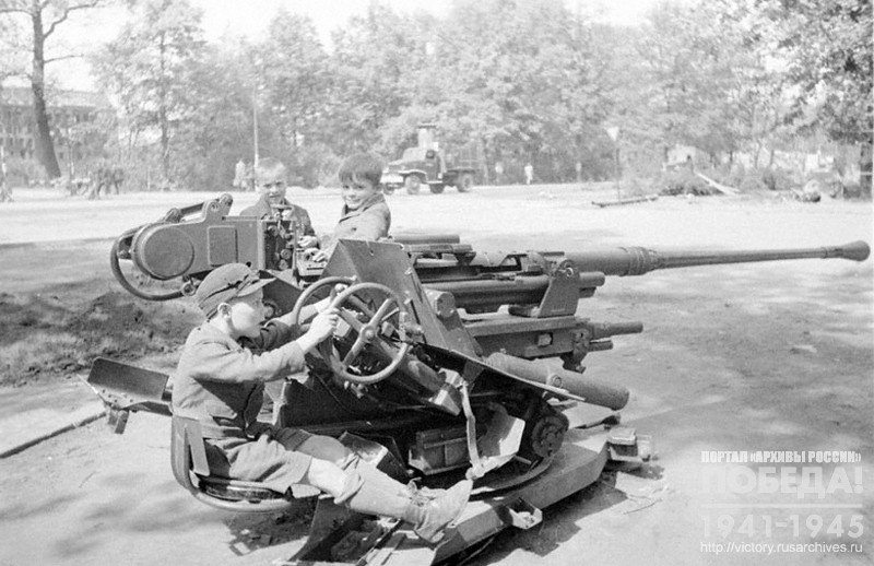 Berlin children play with anti-aircraft guns left by the Germans troops on the streets of the city