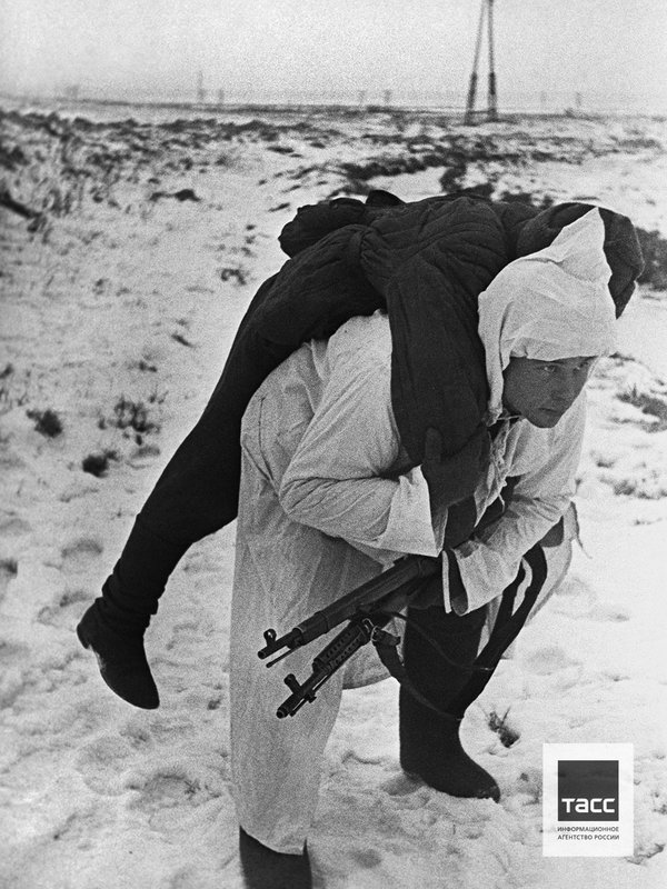 Red Army soldier carries his wounded brother-in-arms out of the battlefield. December, 1941.