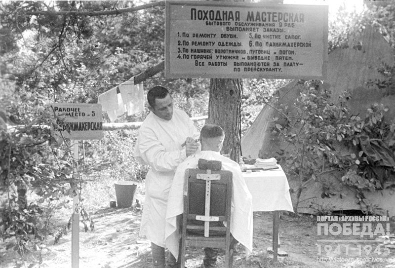 Походная мастерская бытового обслуживания на одном из участков Западного фронта.  Парикмахер во время выполнения стрижки