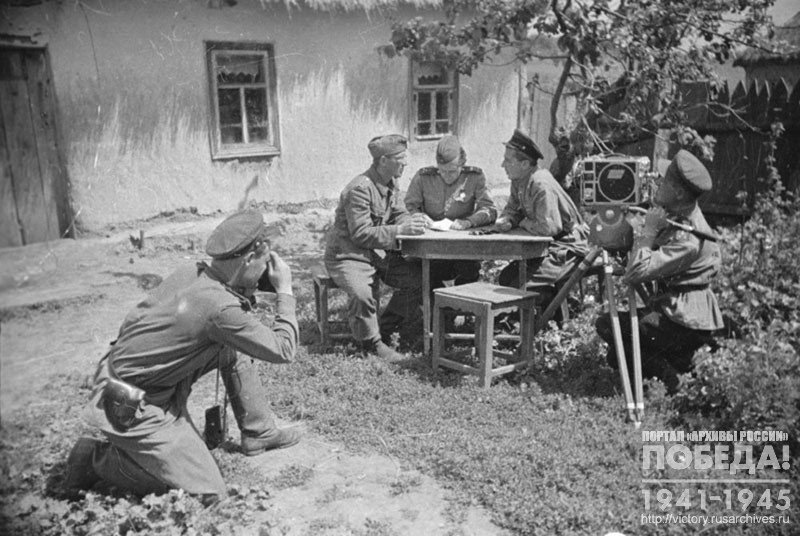 Кинооператор И.Ф. Малов и фотокорреспондент О.Б. Кнорринг ведут съемку допроса перебежчика – немецкого солдата старшего ефрейтора Альфонса Баумхора, добровольно перешедшего на сторону советских войск. Допрос ведет капитан С.А. Миронов, переводчик Ионис