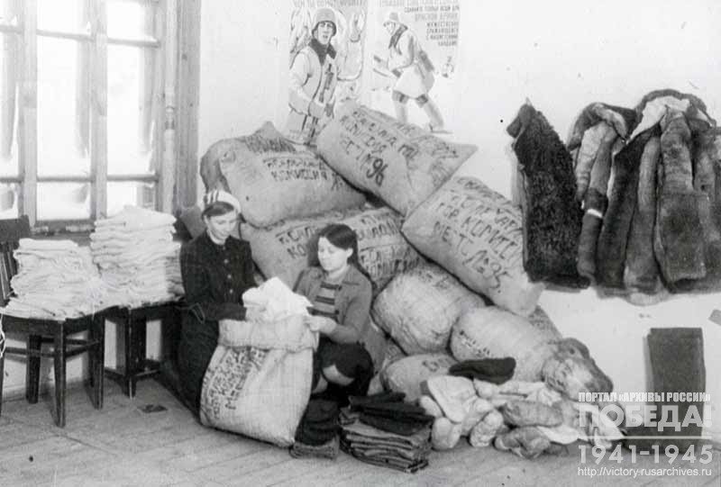 Storekeeper Z. Milyutina and receptionist N. Tarlatova pack warm clothes to be sent to the front as gifts to Soviet soldiers