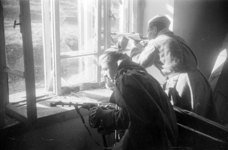 Разведчики старшина И.В.Булгаков и сержант П.С.Мельников стреляют из окна дома