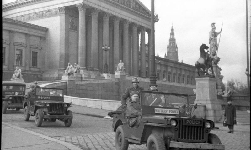 «Совместный военный патруль союзных государств отъезжает от здания австрийского парламента в Вене.»