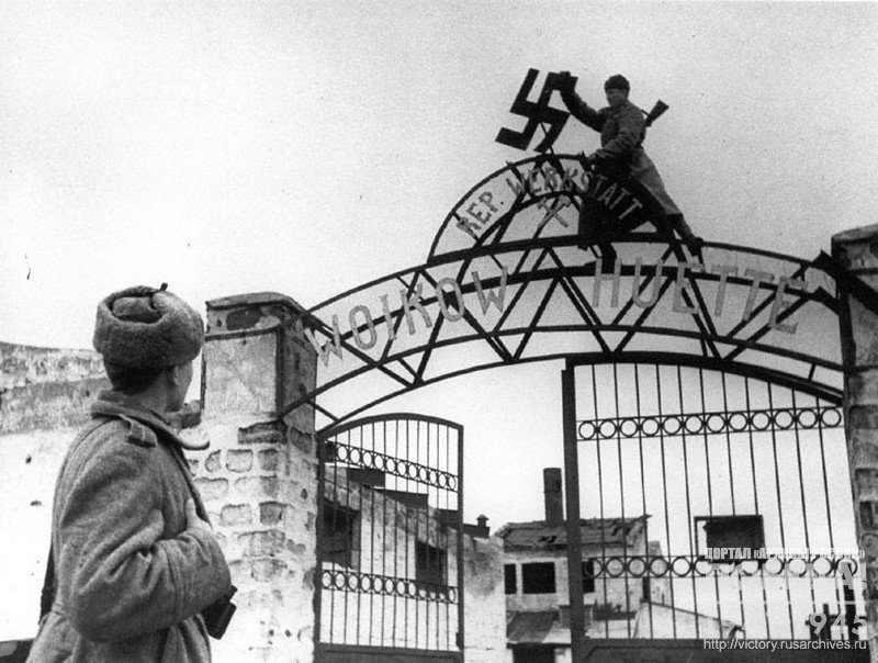 Soviet soldiers  shooting down fascist swastika from the entrance to the territory of plant named after Voikov in liberated Kerch city