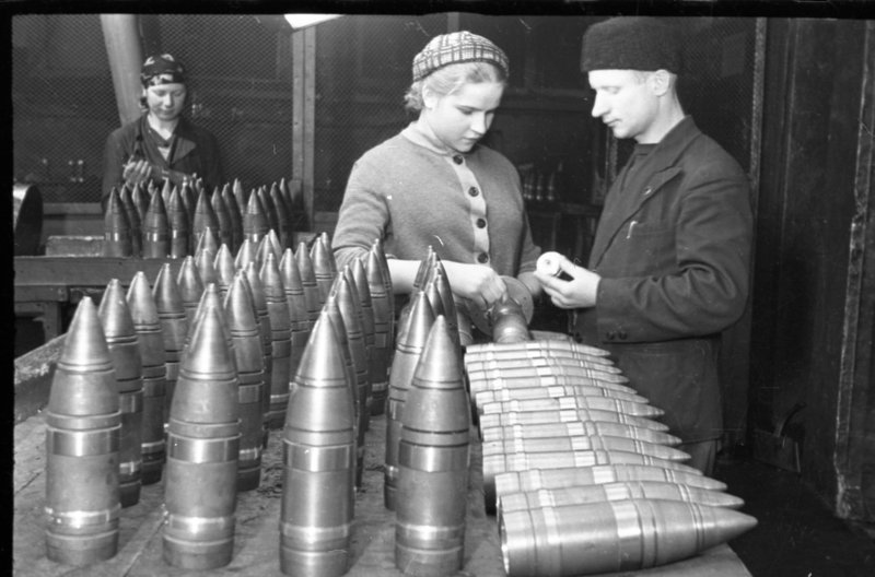 «Москва. Н-ский завод.  Приёмщица Байбакова (в центре) проверяет шаблоном корпус 76-мм бронебойного снаряда.»