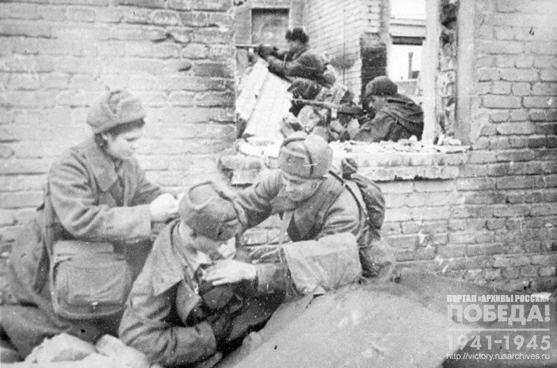 Combat medic F.P.Sternov, who carried 92 wounded off the battlefield, and nurse L.Barlina giving medical assistance to a wounded soldier