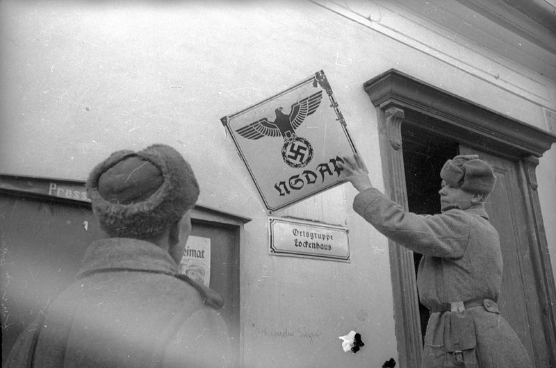 Советские солдаты снимают немецкие вывески со здания ремонтных мастерских