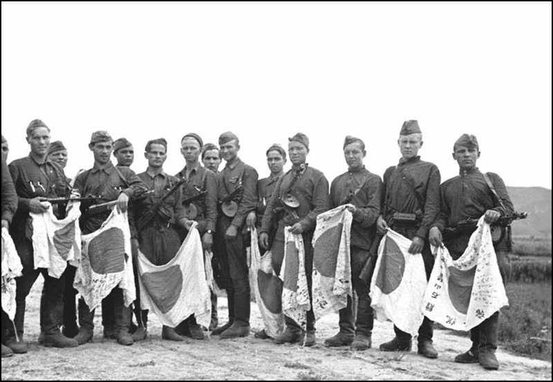 Soviet soldiers holding captured Japanese flags
