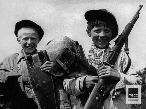 Школьники освобожденного пункта Старица Н. Белов и П. Башилов (слева направо) во время сдачи собранных ими немецких трофеев