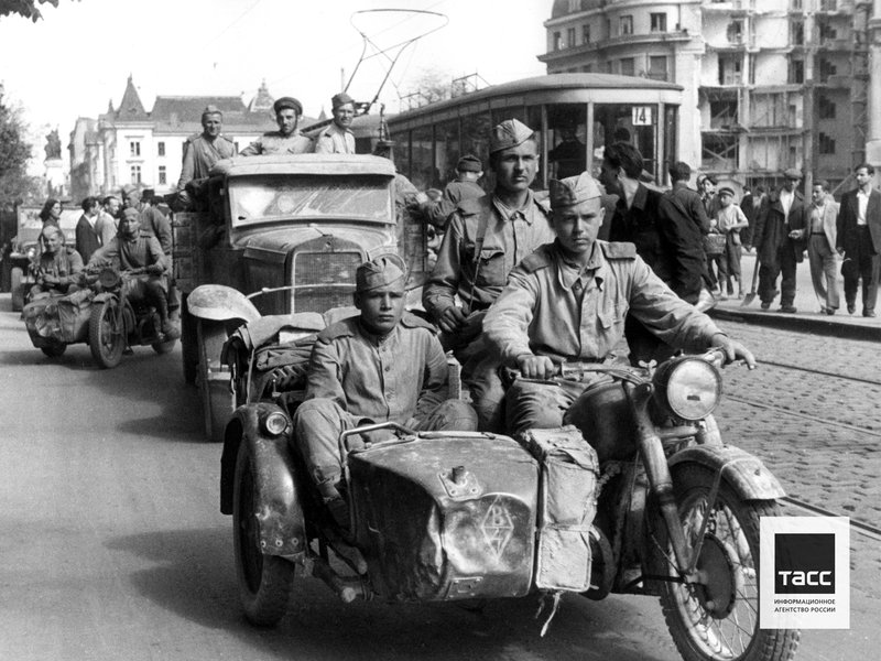 Soviet soldiers ride on motorcycles down a street in Bucharest, 1944. Photo by Mikhail Ozersky/TASS