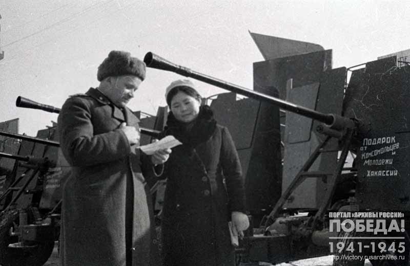 Representative of the Youth of the Khakas Autonomous Region E. Abdina passes to Engineer-Major P. Nikonov antiaircraft guns built by the workers of the region