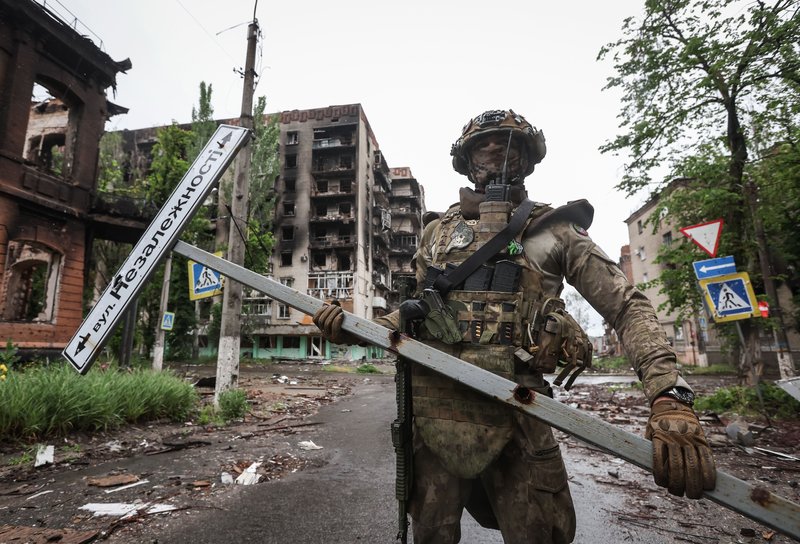 Ситуация в Артемовске. Россия. ДНР. Артемовск. Военнослужащий частной военной компании (ЧВК) "Вагнер" с дорожным знаком на одной из улиц города