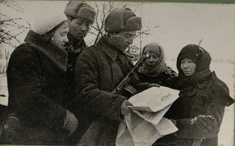 Image: In a liberated village, a political instructor reads a newspaper to residents