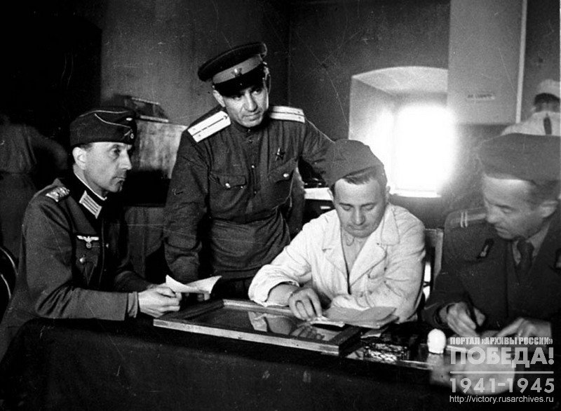 Члены совета при столовой лагеря военнопленных № 160 за обсуждением очередного меню: немецкий офицер от управления лагерем и заведующий столовой румын младший лейтенант Згурский