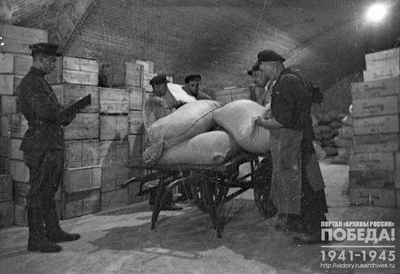German workers load a cart with sacks of flour in the 1st section of the Mitte District of the Central Food Warehouse of the Military Commandant's office