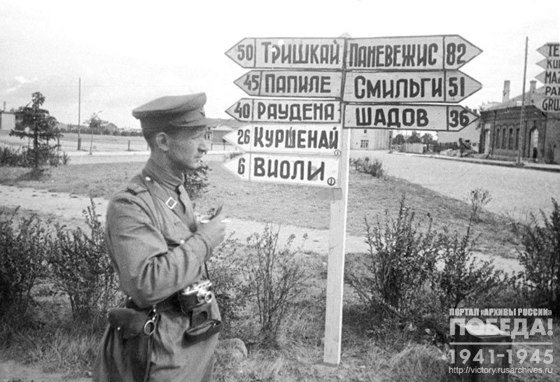 Военный фотокорреспондент фронтовой газеты «Вперёд на врага» Б.Е. Вдовенко возле указателей на фронтовой дороге в Литовской ССР
