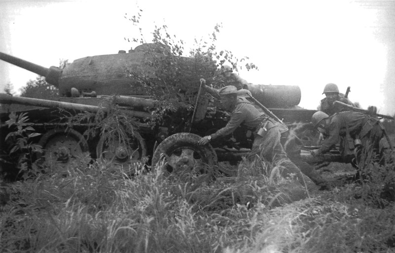 Расчет советской 76-мм пушки ЗиС-3 меняет позицию на Сахалине у танка Т-34-85