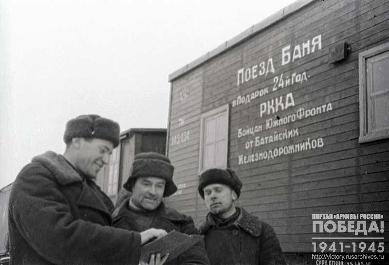 Director of the Batay wagon depot V. Ustinchenko, master M. E. Ukbennikov and metalworker P. Iryulin at one of the cars of the train-bath, built as a gift from the Batay depot workers to the soldiers of the Southern Front