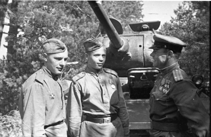 «1-й Украинский фронт. Командир 64-й гвардейской танковой бригады дважды Герой Советского Союза подполковник И.Н. Бойко общается с солдатами у танка Т-34-85.»