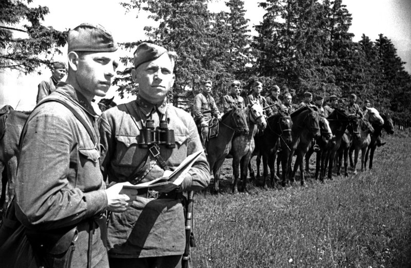 Cavalry recon platoon before a combat operation. Political instructor S.V. Kozlov (left) and Lieutenant A.A. Vasilistov clarify the plan of the operation.