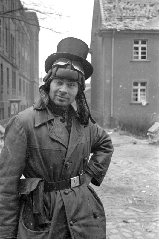 Soviet tanker in a tank helmet and a top hat on the street of Berlin