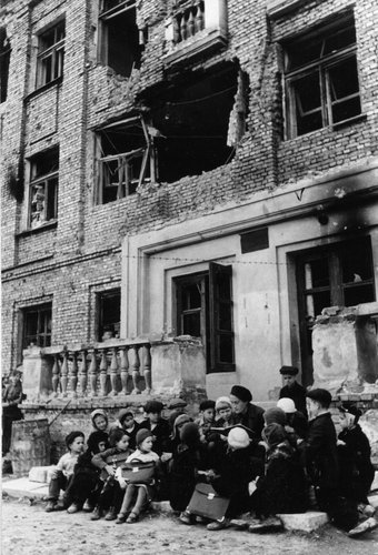 Teacher and pupils on the porch of a destroyed building