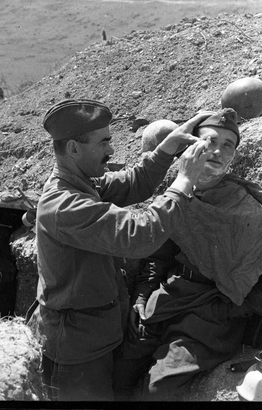 Фронтовая парикмахерская. Бойцы 4-й роты 2-го батальона 162-го стрелкового полка 95-й стрелковой дивизии Приморской армии в минуты отдыха. («Парикмахер» - красноармеец Эдхизашвили, «клиент» - политрук Прудкой К.Ф.).