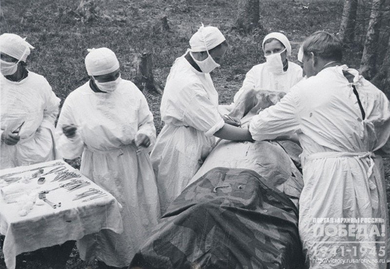 Surgeons operating on a wounded in a field hospital