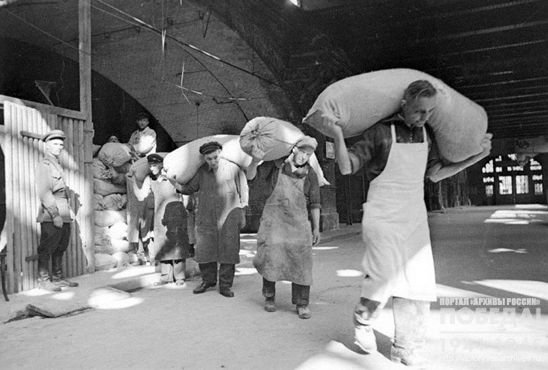 German workers carrying bags of flour in the 1st section of the Mitte District of the Central Food Warehouse of the Military Commandant's office