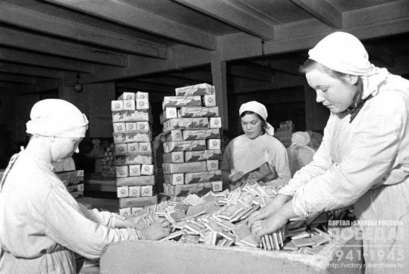 Работницы кондитерской фабрики «Большевик» П.В. Красивова, А.Г. Малов и А.Л. Полякова упаковывают галеты для отправки на фронт