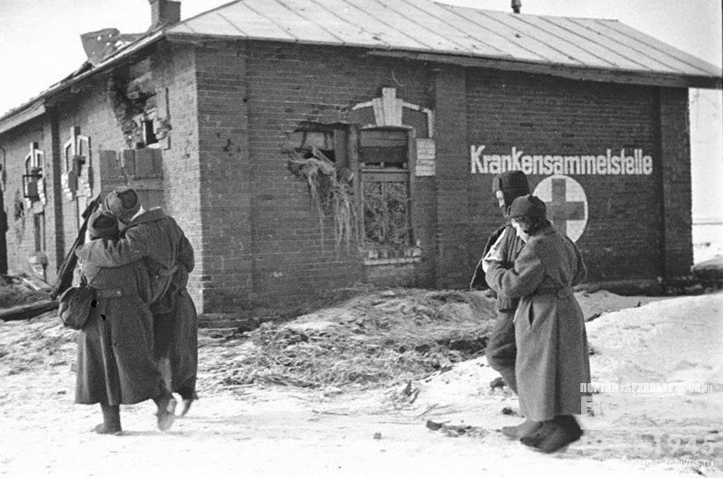 Прибывшие раненые направляются в госпиталь, на стенах которого еще сохранилась немецкая надпись