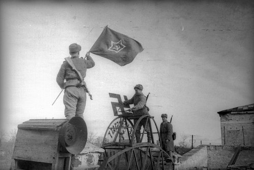 Советские солдаты срывают свастику и водружают красный флаг на ворота завода имени Войкова